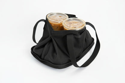 A black fabric insulated tote bag with two handles, shown on a white background with two lidded plastic cups placed inside with snaps to secure